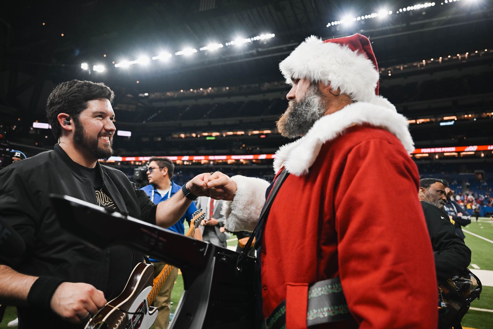 Noah Scott and Jason Kelce, in a Santa suit, bumping fists on the field