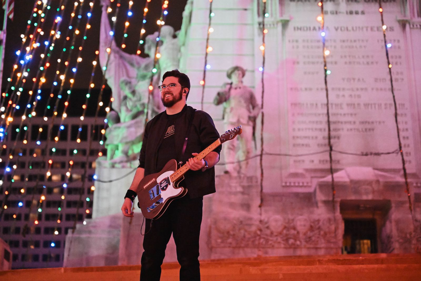 Noah Scott with the guitar at the Soldiers' and Sailors' Monument, lit for the holidays