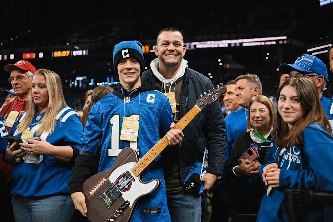 A young Colts fan holding the guitar with his family