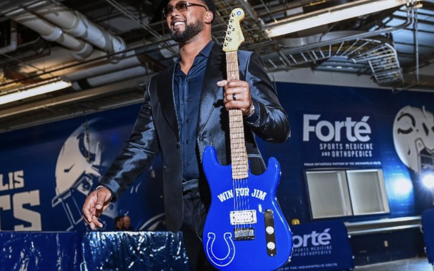 Colts defensive tackle DeForest Buckner smiling as he carries the blue Win for Jim guitar