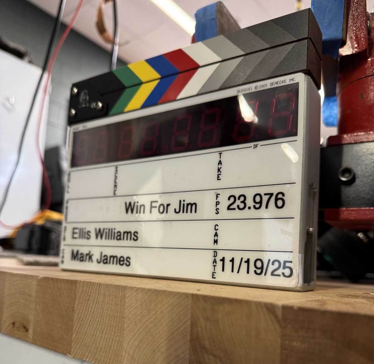 A film slate reading Win For Jim on a Guitar Lab workbench